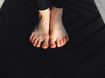 Focused view on bare feet on a dark mat.